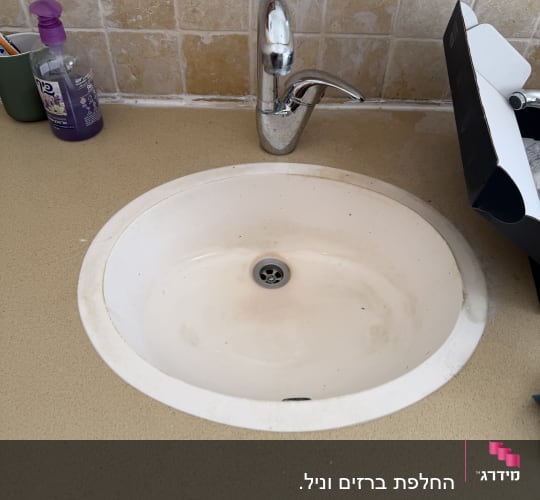 כיור עם ברז ומתקן לסבון על משטח עבודה